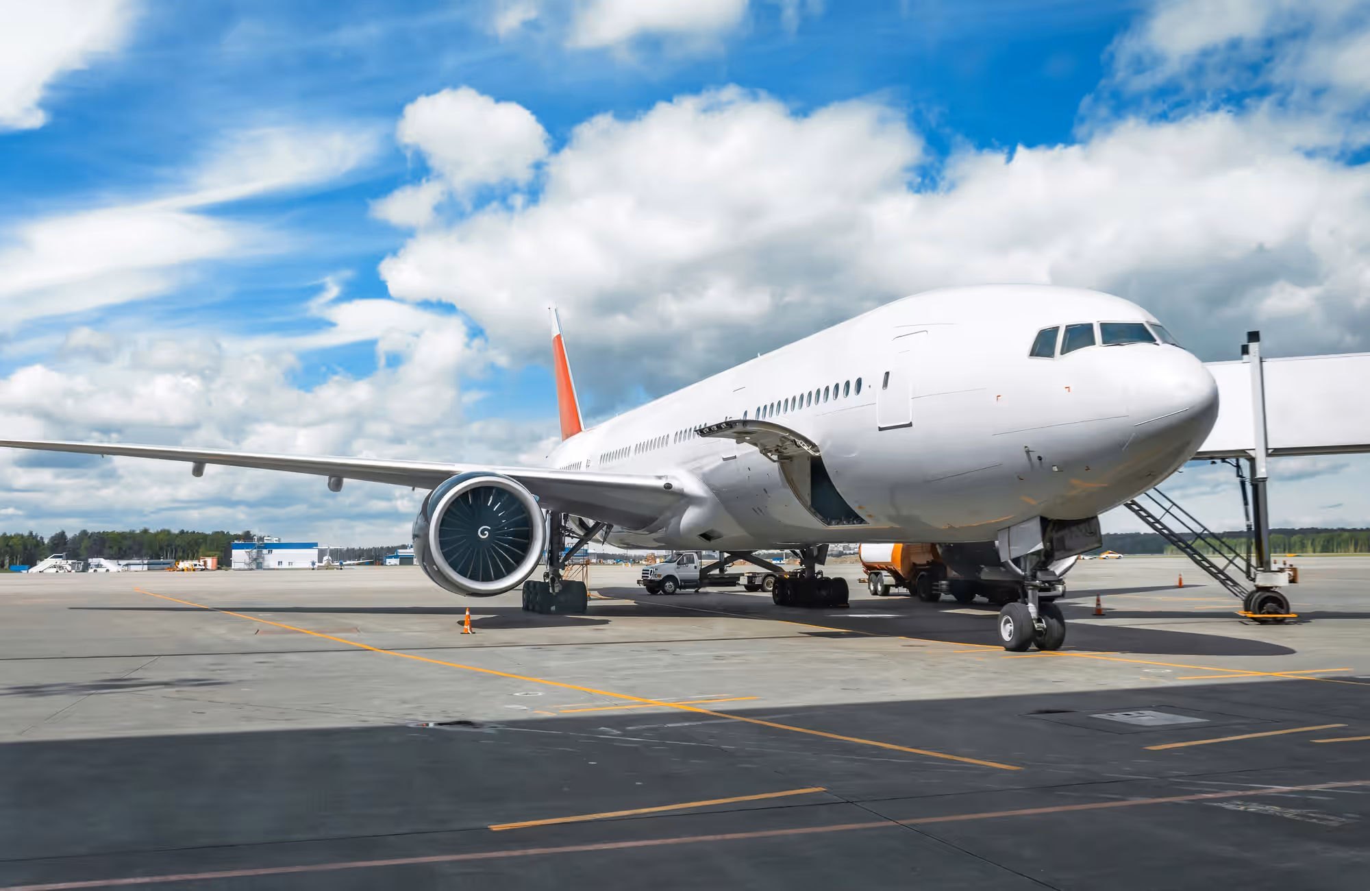 Large white commercial airplane parked at an airport gate under a partly cloudy sky.